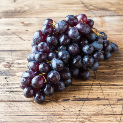 bunch of fresh black grapes on a wooden wooden table are a selective focus.